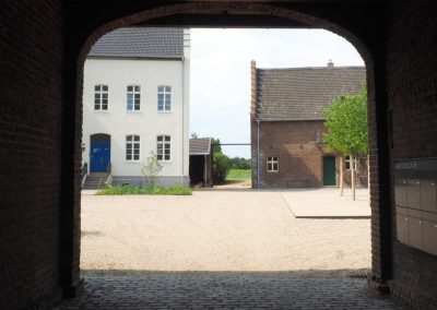 Ansicht einer Hofanlage mit Berliner Fenstern und Türen von frovin durch einen Torbogen.