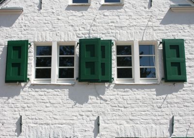Außenansicht eines Hauses mit Berliner Sprossenfenstern und grünen Fensterläden von frovin
