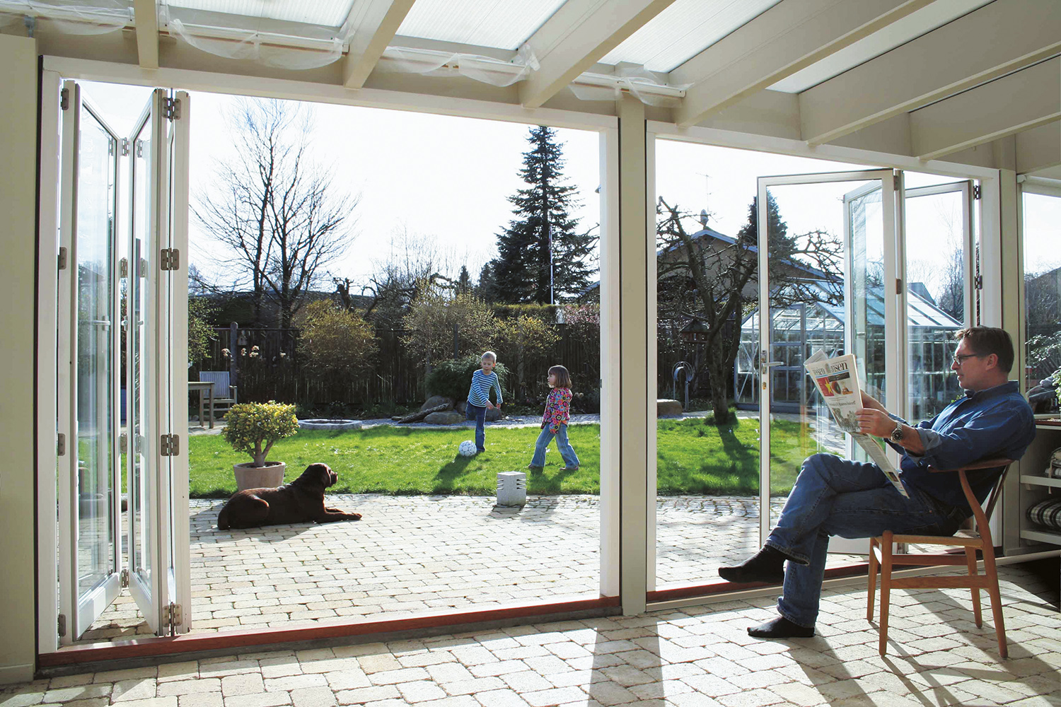 Weiße geöffnete Falttür gibt Blick in den Garten frei
