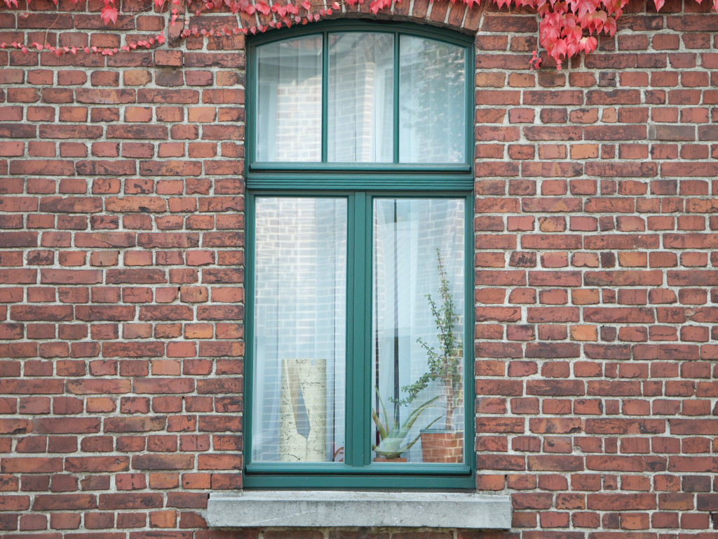 Grünes, doppelflügliges Hamburger Fenster in Klinkerfassade